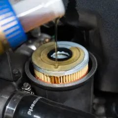 Öl wird in einen neuen Ölfilter gegossen, der in einem BMW E46 Motor sitzt.