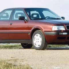Roter Audi 80 B4 Limousine von vorne rechts auf Schotterweg.
