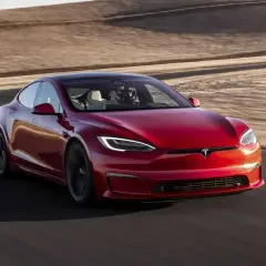Roter Tesla Model S Plaid fährt auf einer Rennstrecke mit Wüstenlandschaft im Hintergrund.