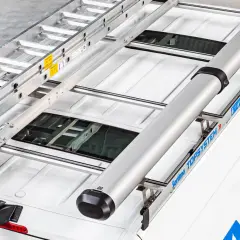 Dachgepäckträger mit Leiter und Rohr auf einem weißen Lieferwagen.