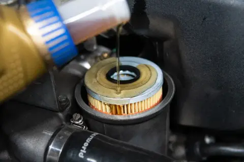 Öl wird in einen neuen Ölfilter gegossen, der in einem BMW E46 Motor sitzt.