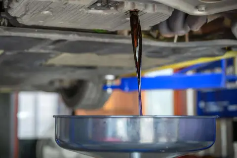 Altöl fließt aus dem Getriebe eines Autos in eine Auffangschale.