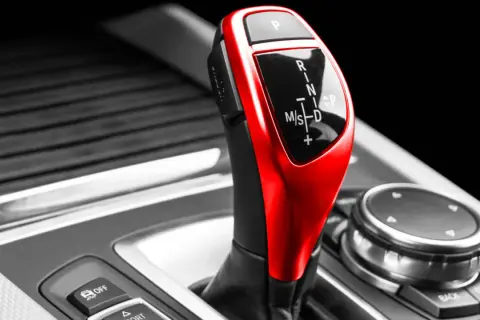 Roter Automatikschalthebel mit Ganganzeige (P, R, N, M/S, D) in einem Auto.