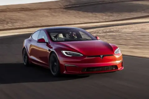Roter Tesla Model S Plaid fährt auf einer Rennstrecke mit Wüstenlandschaft im Hintergrund.