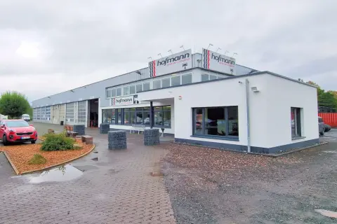 Gebäude von Reifen Hofmann Bebra mit roten Auto davor.