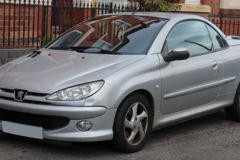 Silberner Peugeot 206 CC mit offenem Verdeck, geparkt vor einer Ziegelmauer.