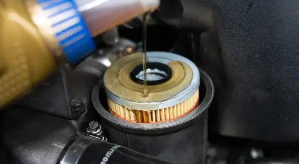 Öl wird in einen neuen Ölfilter gegossen, der in einem BMW E46 Motor sitzt.