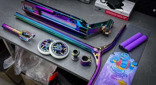 Bunte Stunt-Scooter-Teile: Deck, Gabel, Lenker, Rollen und Griffe.