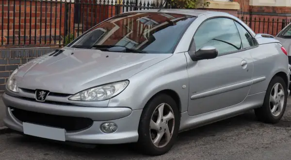 Silberner Peugeot 206 CC mit offenem Verdeck, geparkt vor einer Ziegelmauer.