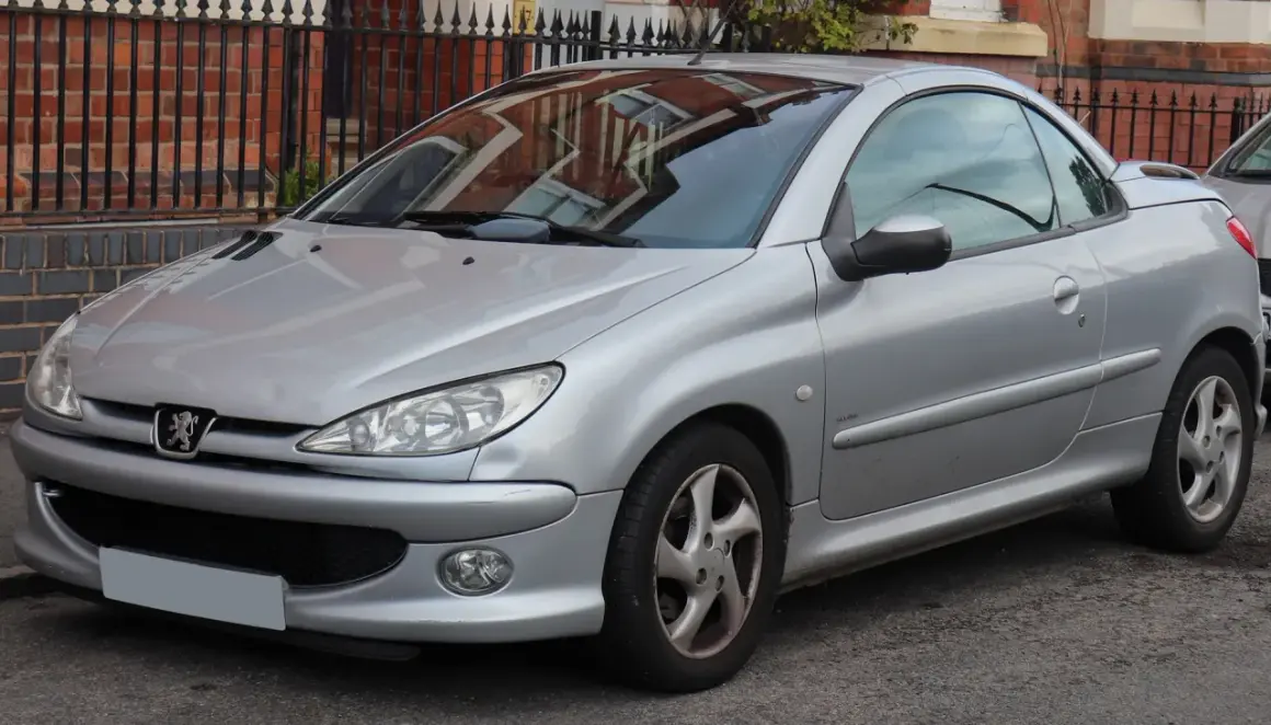 Silberner Peugeot 206 CC mit offenem Verdeck, geparkt vor einer Ziegelmauer.