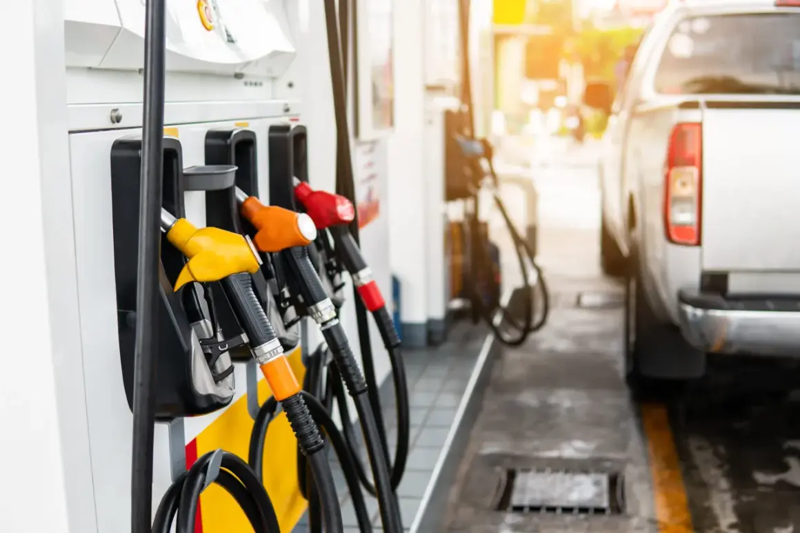 Zapfsäulen mit bunten Zapfpistolen und einem Teil eines Autos an einer Tankstelle.