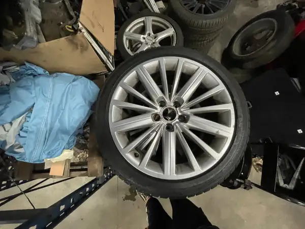 Mehrere Autoreifen, darunter ein silberner Alufelgen-Reifen im Vordergrund.