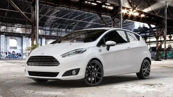 Weißer Ford Fiesta mit schwarzen Felgen in einer Industriehalle.