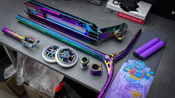 Bunte Stunt-Scooter-Teile: Deck, Gabel, Lenker, Rollen und Griffe.