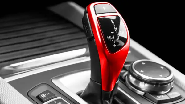 Roter Automatikschalthebel mit Ganganzeige (P, R, N, M/S, D) in einem Auto.