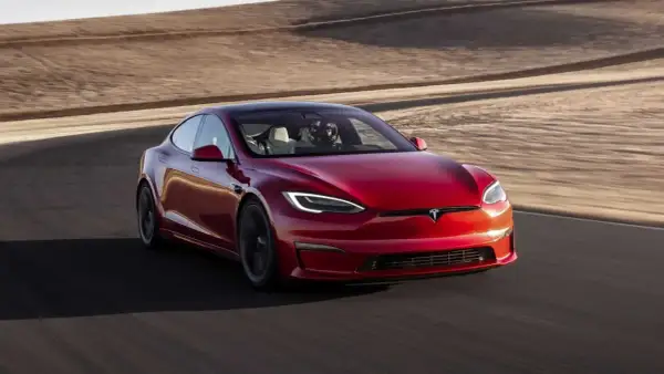 Roter Tesla Model S Plaid fährt auf einer Rennstrecke mit Wüstenlandschaft im Hintergrund.