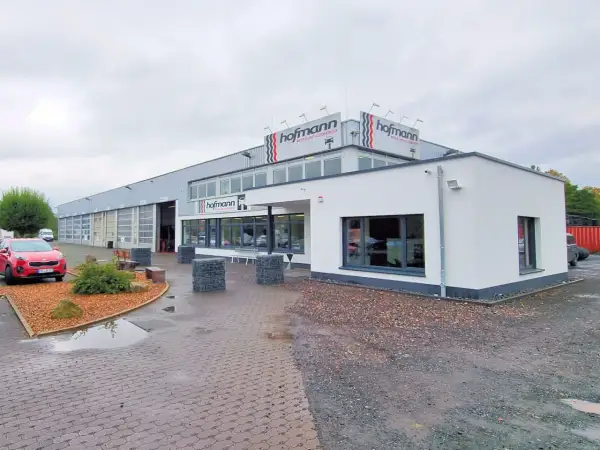 Gebäude von Reifen Hofmann Bebra mit roten Auto davor.